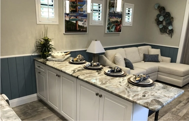 A living room with white furniture and marble counter tops.