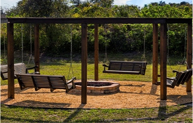 A fire pit with swings and benches in the middle of it.