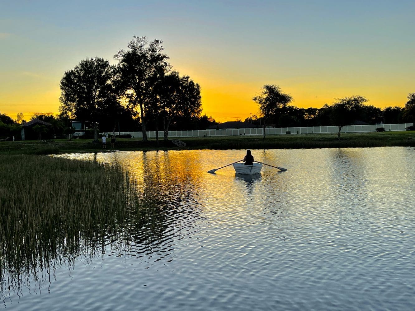 A person in a boat on the water at sunset.