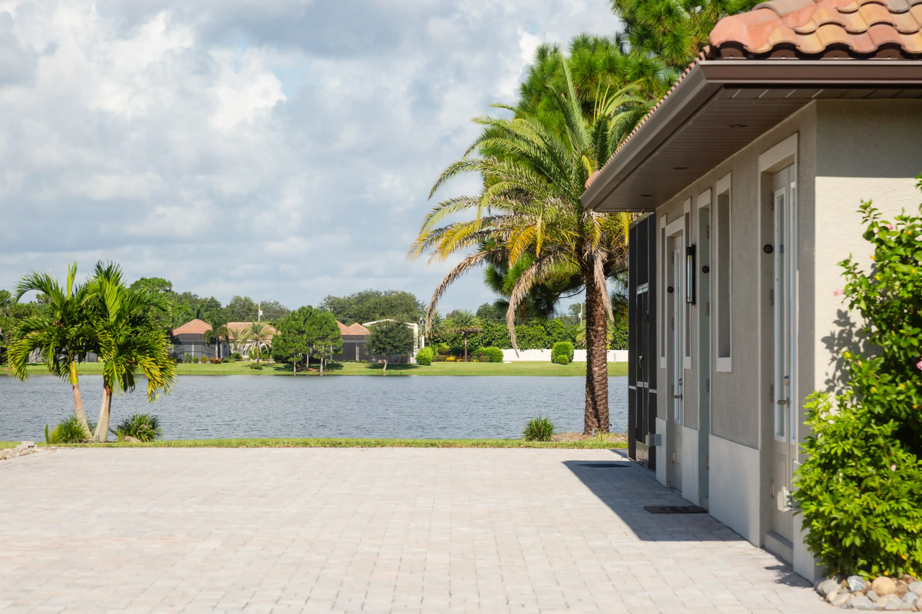 A house with a lake and palm trees in the background.