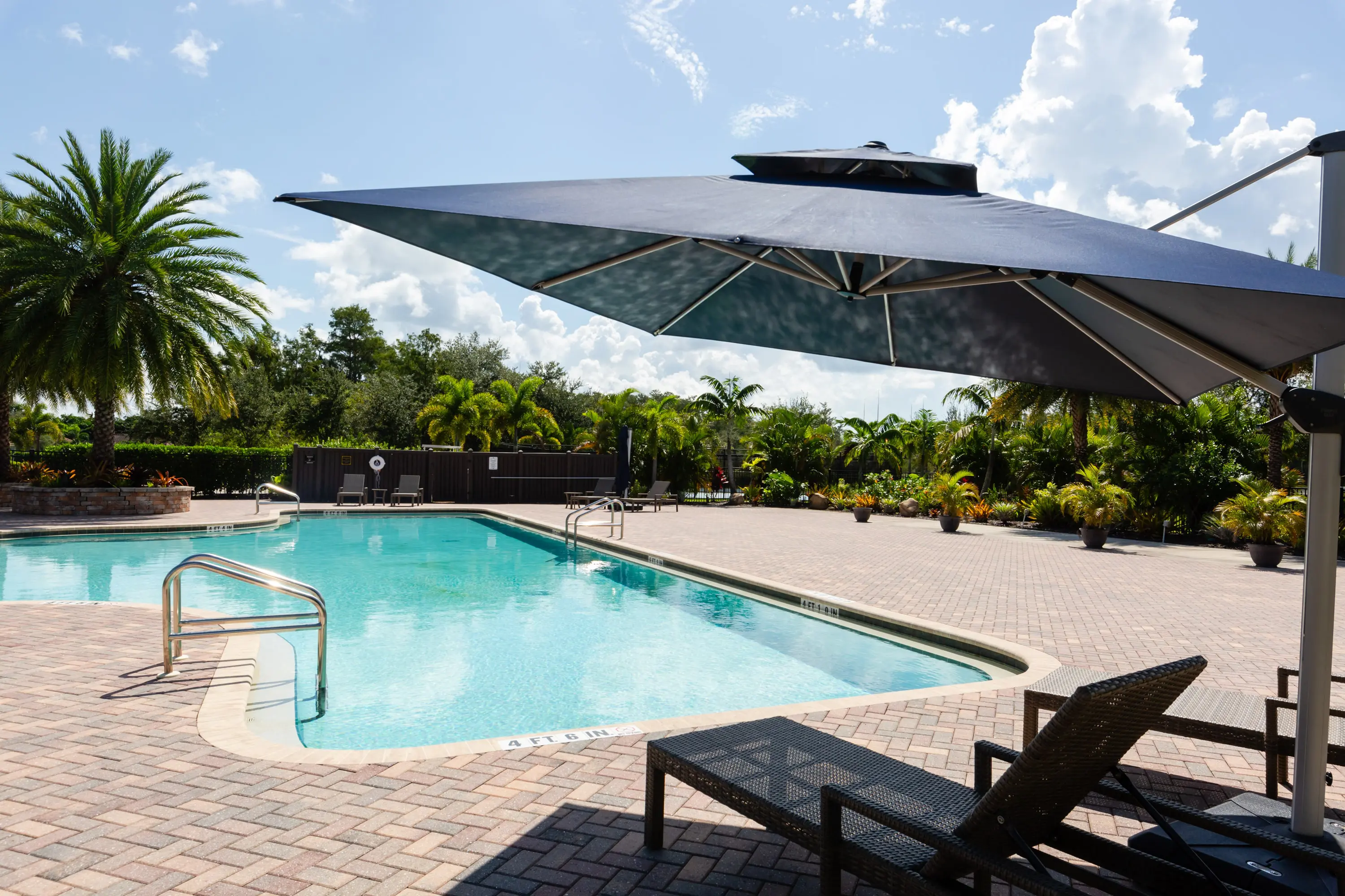 A pool with an umbrella over it and chairs