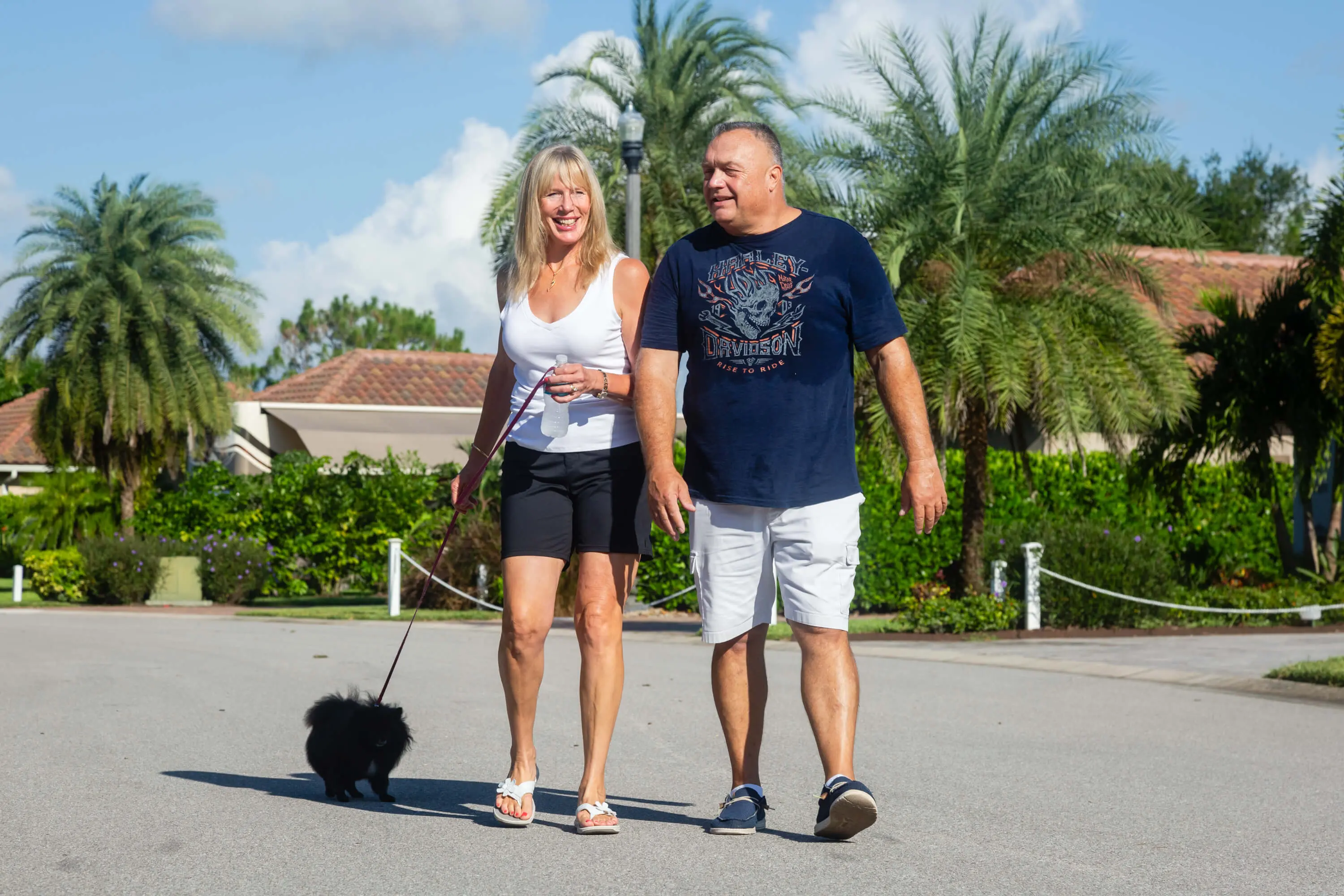 A man and woman walking their dog on the street.