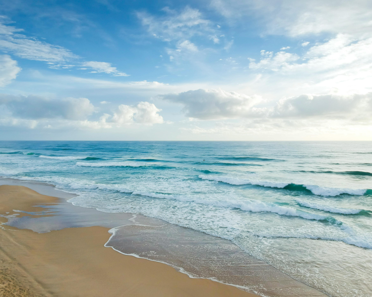 A beach with waves coming in from the ocean.